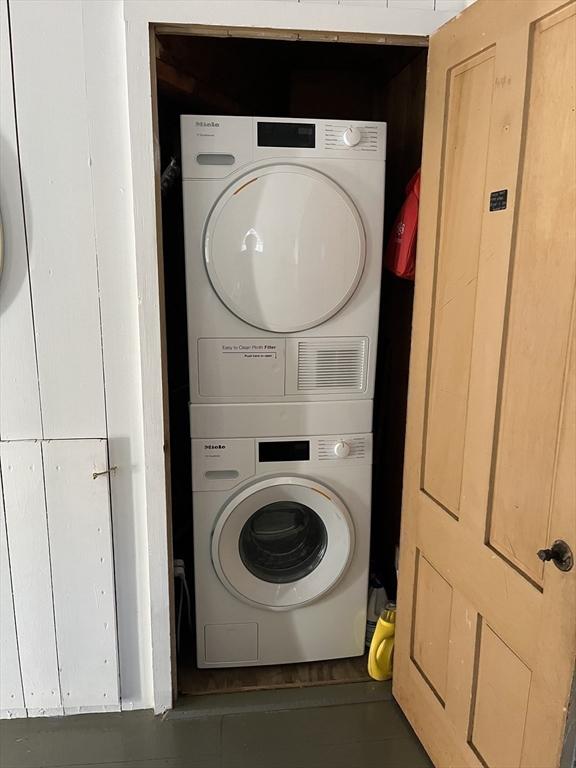 washroom with dark tile patterned floors and stacked washer / dryer