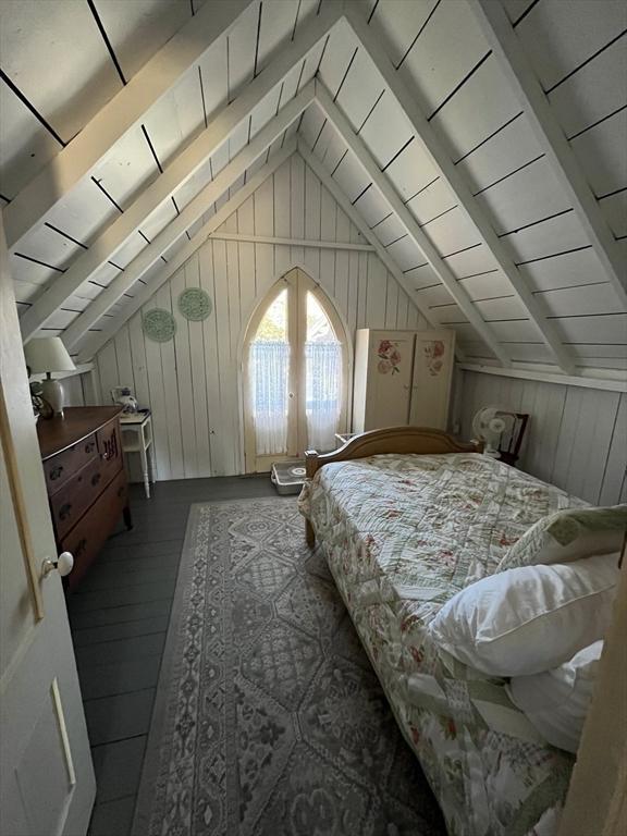 bedroom with lofted ceiling with beams, hardwood / wood-style flooring, wooden walls, and wood ceiling