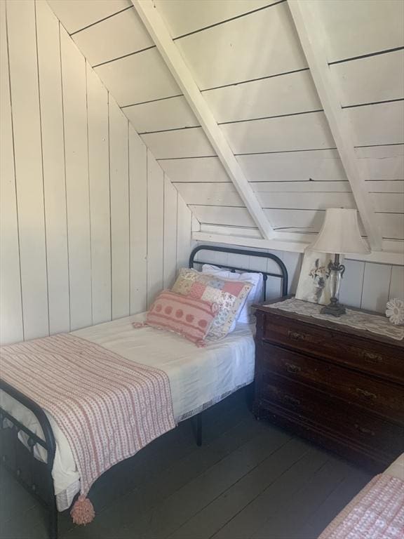 bedroom with beamed ceiling, hardwood / wood-style flooring, and wooden walls