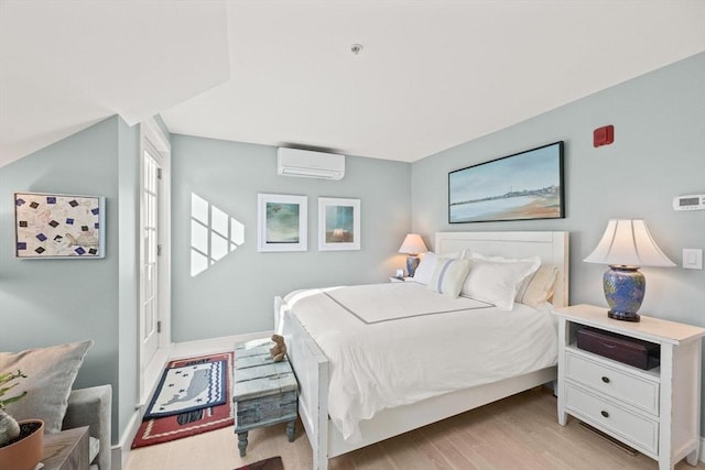 bedroom featuring an AC wall unit and light hardwood / wood-style floors