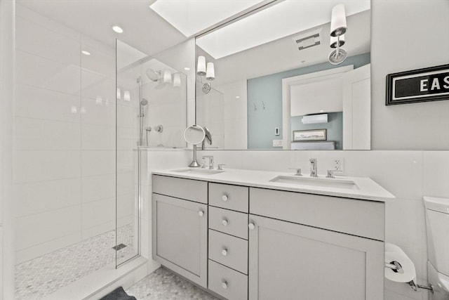 bathroom featuring toilet, vanity, and a tile shower