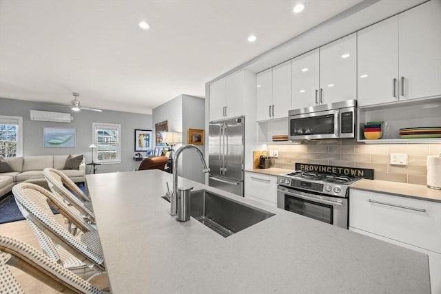 kitchen featuring decorative backsplash, sink, white cabinetry, a wall mounted air conditioner, and stainless steel appliances