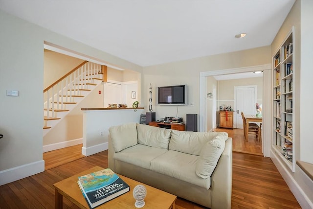 living area with stairs, baseboards, and hardwood / wood-style floors