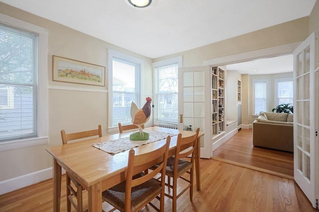 dining area with light wood-style flooring, french doors, and a healthy amount of sunlight