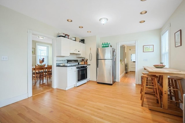 kitchen with light wood finished floors, a wealth of natural light, white gas stove, and freestanding refrigerator