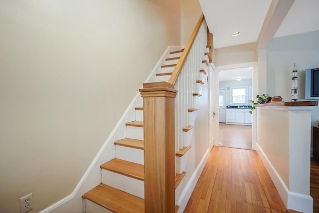 staircase featuring recessed lighting, baseboards, and wood finished floors