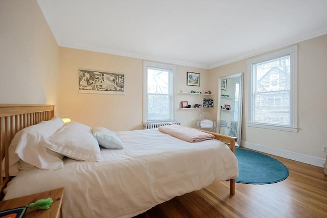 bedroom with crown molding, multiple windows, wood finished floors, and baseboards