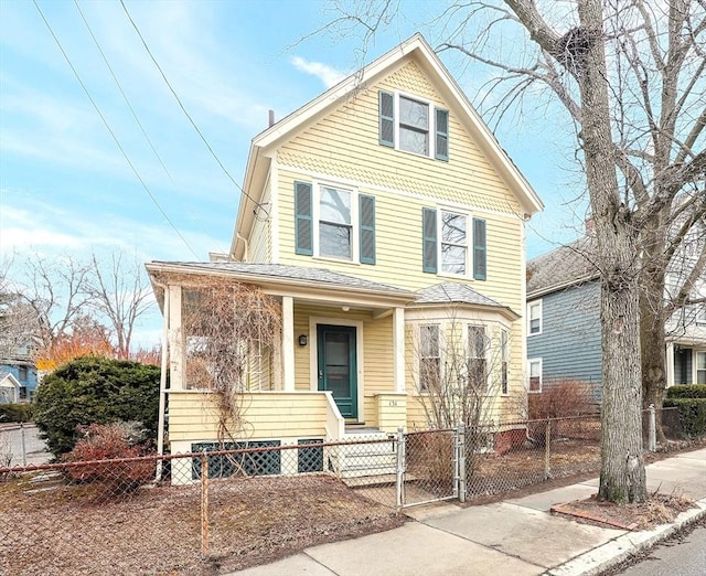 traditional style home featuring a fenced front yard and a porch