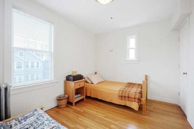 bedroom with radiator heating unit and light wood finished floors