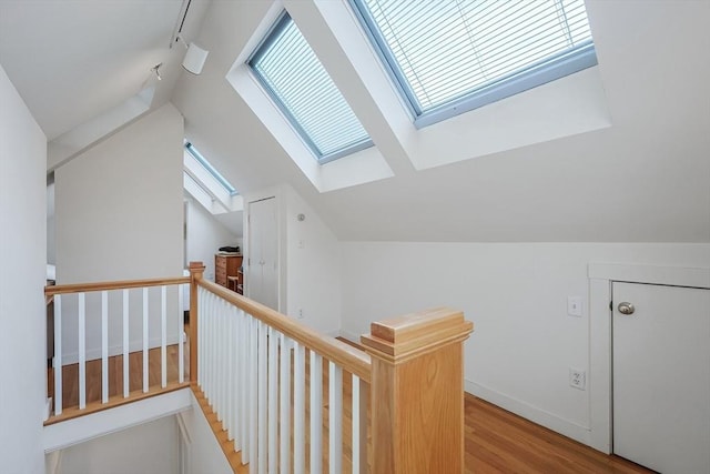 additional living space featuring baseboards, lofted ceiling with skylight, and wood finished floors