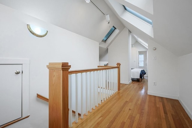 additional living space with vaulted ceiling with skylight, wood finished floors, and baseboards