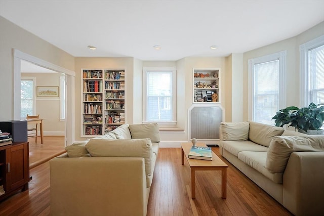 living room with built in features, plenty of natural light, and wood finished floors