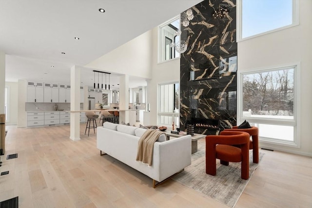 living room with a fireplace, a high ceiling, and light wood-type flooring