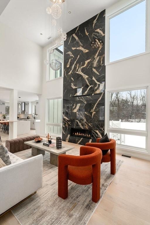 living room with an inviting chandelier, a healthy amount of sunlight, a premium fireplace, and wood-type flooring