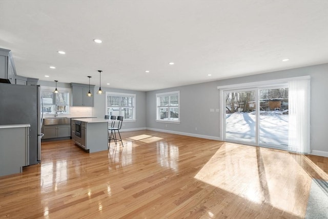 kitchen with light countertops, gray cabinets, freestanding refrigerator, a center island, and decorative light fixtures