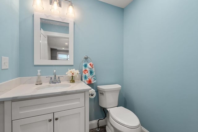 bathroom featuring baseboards, vanity, and toilet