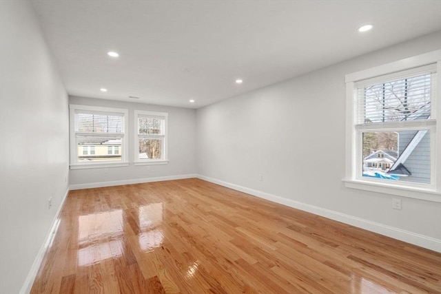 unfurnished room with baseboards, light wood-style flooring, and a healthy amount of sunlight