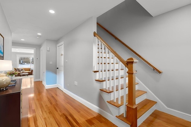 staircase featuring baseboards, wood finished floors, and recessed lighting