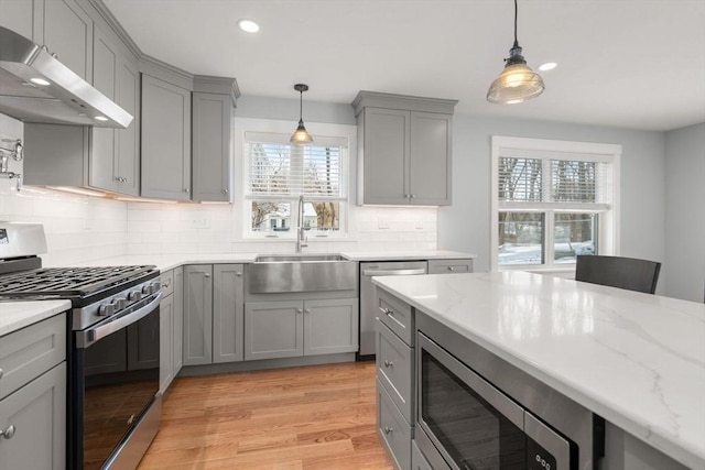 kitchen featuring pendant lighting, appliances with stainless steel finishes, a sink, and under cabinet range hood