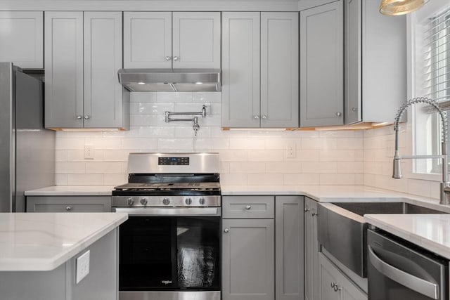 kitchen with stainless steel appliances, gray cabinets, and under cabinet range hood