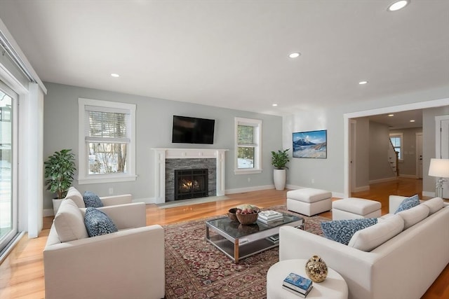 living area featuring a healthy amount of sunlight, light wood-type flooring, a fireplace, and recessed lighting