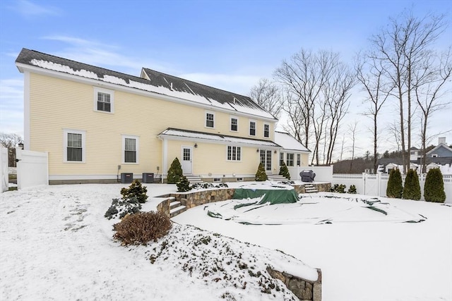 snow covered back of property with central AC unit