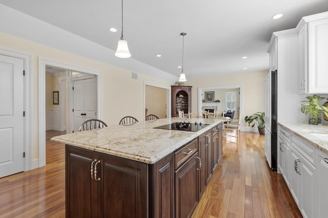 kitchen with black appliances, dark brown cabinets, white cabinets, and pendant lighting