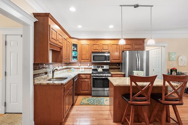 51 Spruce St Unit 51, Northbridge, MA 01534 - kitchen featuring appliances with stainless steel finishes, crown molding, a center island, backsplash, and brown cabinets