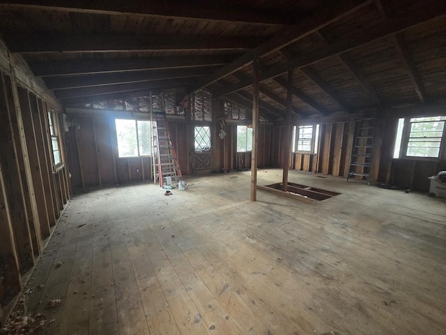 misc room with a healthy amount of sunlight, wood-type flooring, and lofted ceiling with beams
