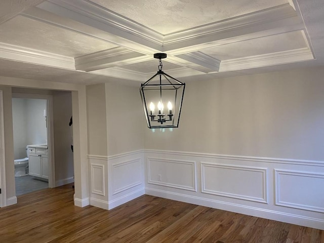 unfurnished dining area featuring coffered ceiling, dark hardwood / wood-style flooring, beamed ceiling, crown molding, and a chandelier