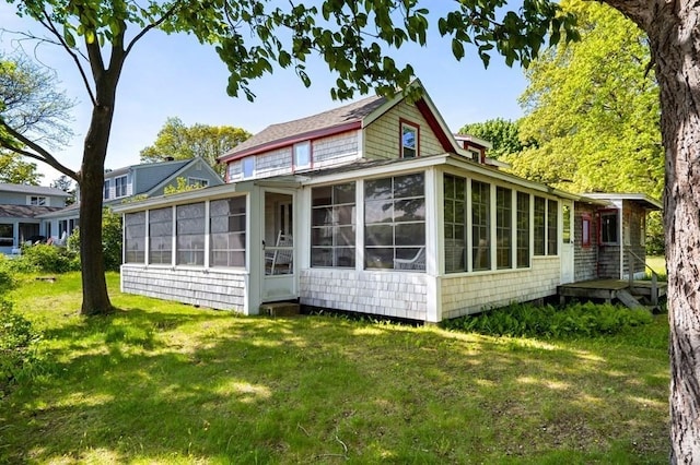 back of property with a lawn and a sunroom