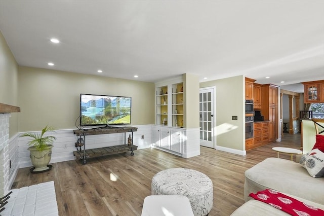 living room with built in features, a fireplace, and light hardwood / wood-style flooring