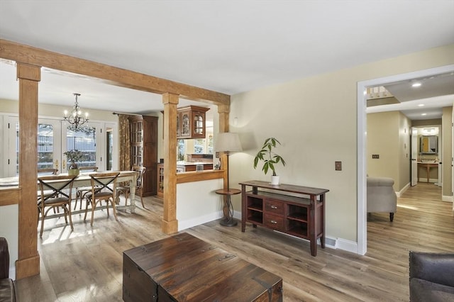 living room with hardwood / wood-style flooring, decorative columns, and a notable chandelier