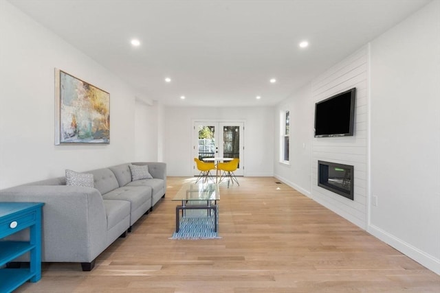 living room featuring baseboards, a fireplace, recessed lighting, and light wood-style flooring