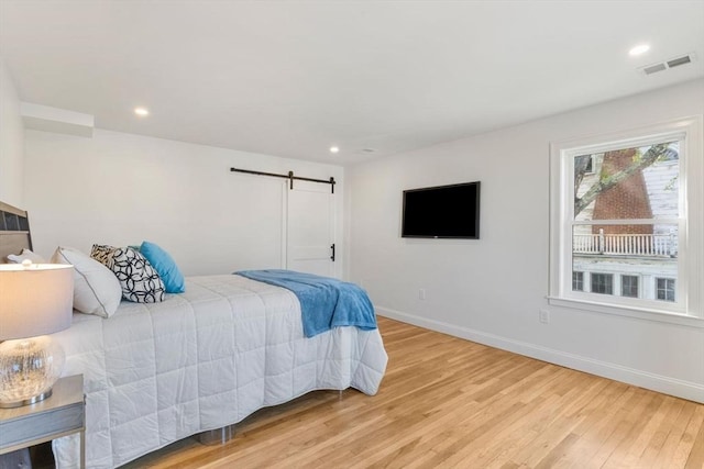 bedroom with visible vents, a barn door, baseboards, light wood finished floors, and recessed lighting