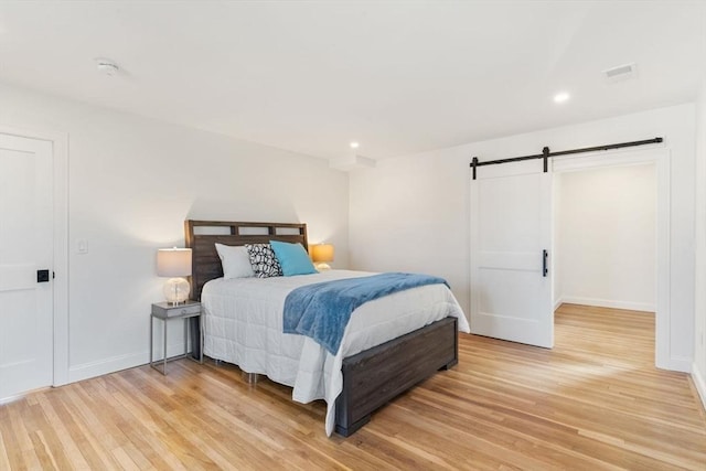 bedroom featuring light wood-style floors, baseboards, recessed lighting, and a barn door