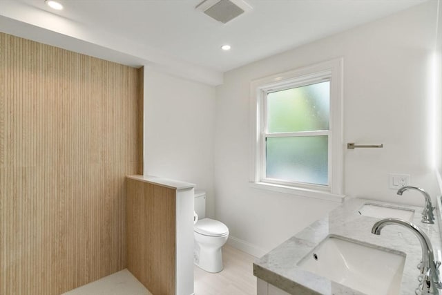 full bath with a sink, double vanity, toilet, recessed lighting, and visible vents