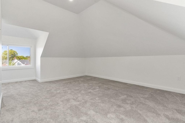 additional living space with carpet flooring, baseboards, and lofted ceiling