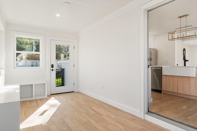 entryway with crown molding, baseboards, light wood-type flooring, recessed lighting, and a sink