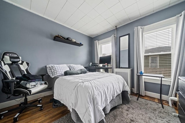 bedroom with ornamental molding and wood finished floors