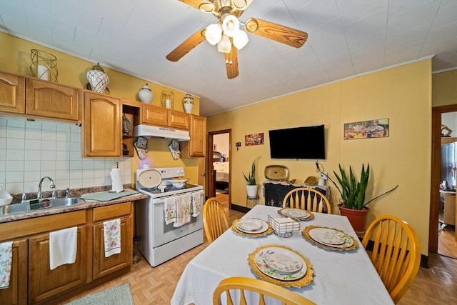 kitchen with a sink, ceiling fan, under cabinet range hood, brown cabinets, and electric stove