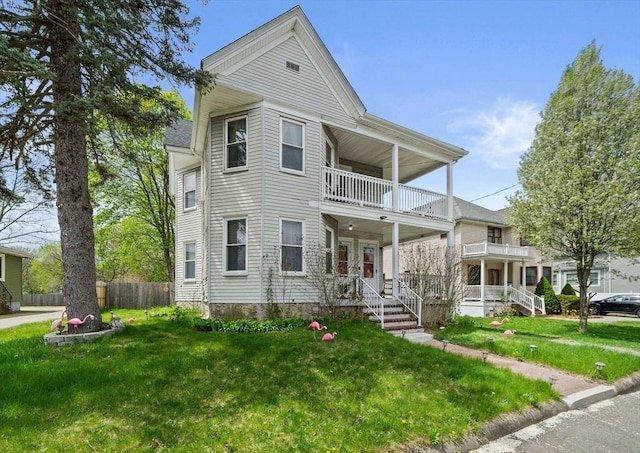 view of front of home with fence, a balcony, and a front lawn