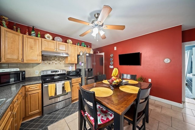 kitchen featuring dark countertops, ceiling fan, stainless steel appliances, under cabinet range hood, and dark tile patterned flooring