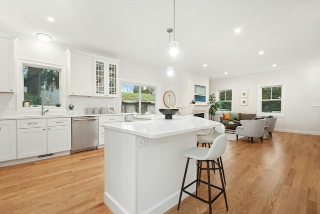 kitchen with sink, stainless steel dishwasher, white cabinetry, and decorative light fixtures