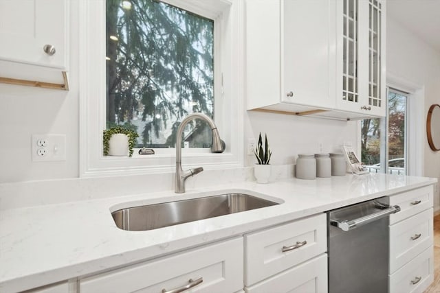 kitchen featuring sink, white cabinets, stainless steel dishwasher, and light stone counters