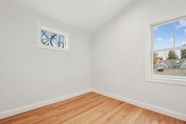 empty room featuring vaulted ceiling and light wood-type flooring