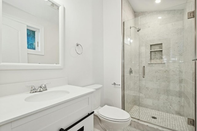 bathroom featuring vanity, toilet, and a shower with shower door