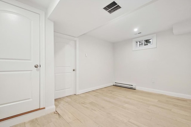 basement with baseboard heating and light hardwood / wood-style floors