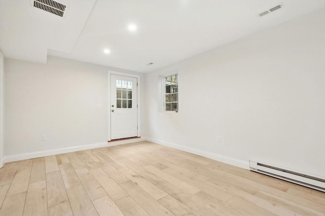 spare room featuring a baseboard radiator and light hardwood / wood-style floors