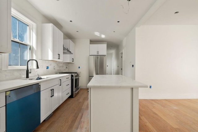 kitchen featuring light wood finished floors, white cabinets, a center island, a sink, and appliances with stainless steel finishes